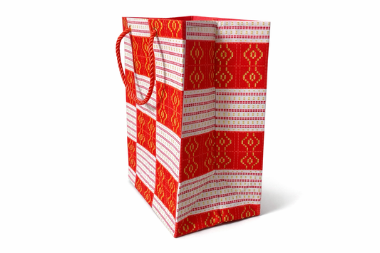 Side view of a red and white patterned gift bag on a white background