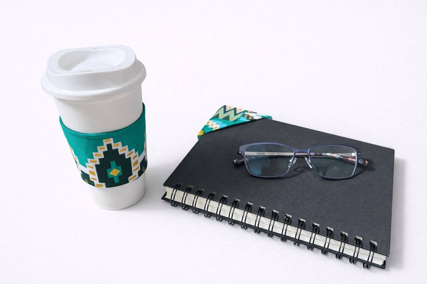 Light green, dark green, dark blue, white, gold cup sleeve and bookmark on a white background