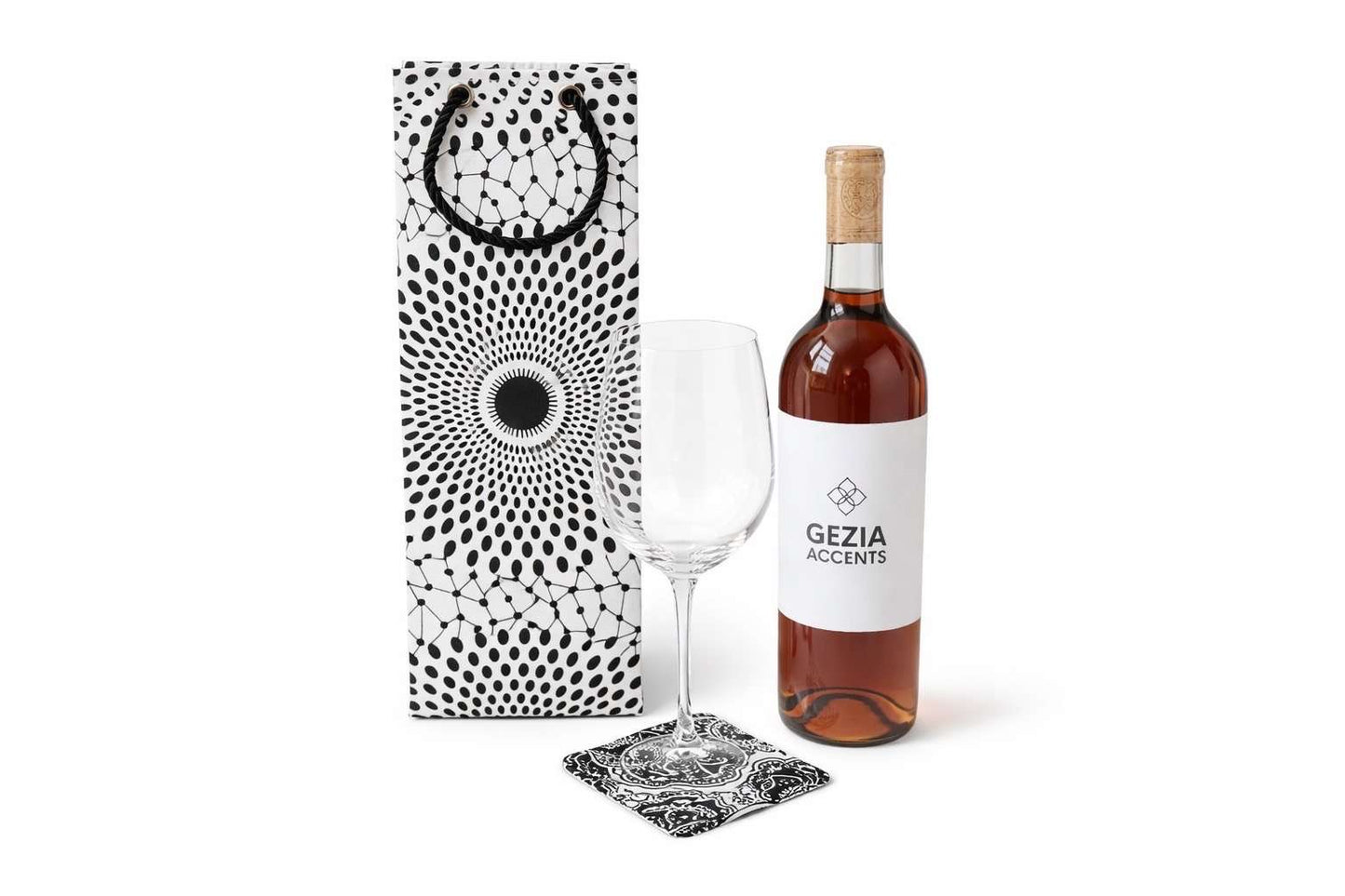 Wine bottle with white and black wine gift bag and matching coaster, and glass on a white background