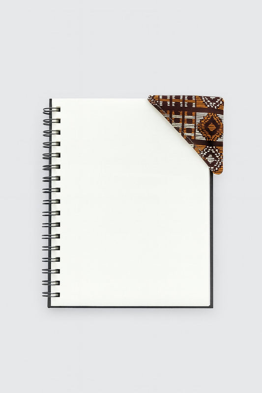 Black spiral-bound notebook with a brown, copper, & gold corner bookmark on a light gray background