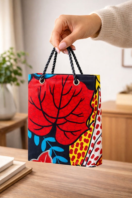 Red, black, aqua, blue, yellow, & white handmade African fabric extra small gift bag in lifestyle shot