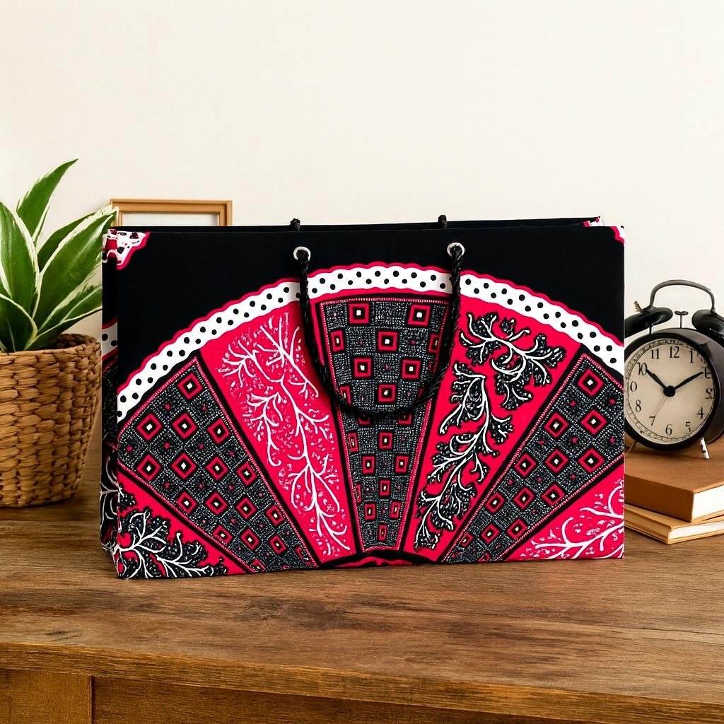 Decorative black, fuchsia, and white patterned bag on a wooden surface with a plant and clock in the background.