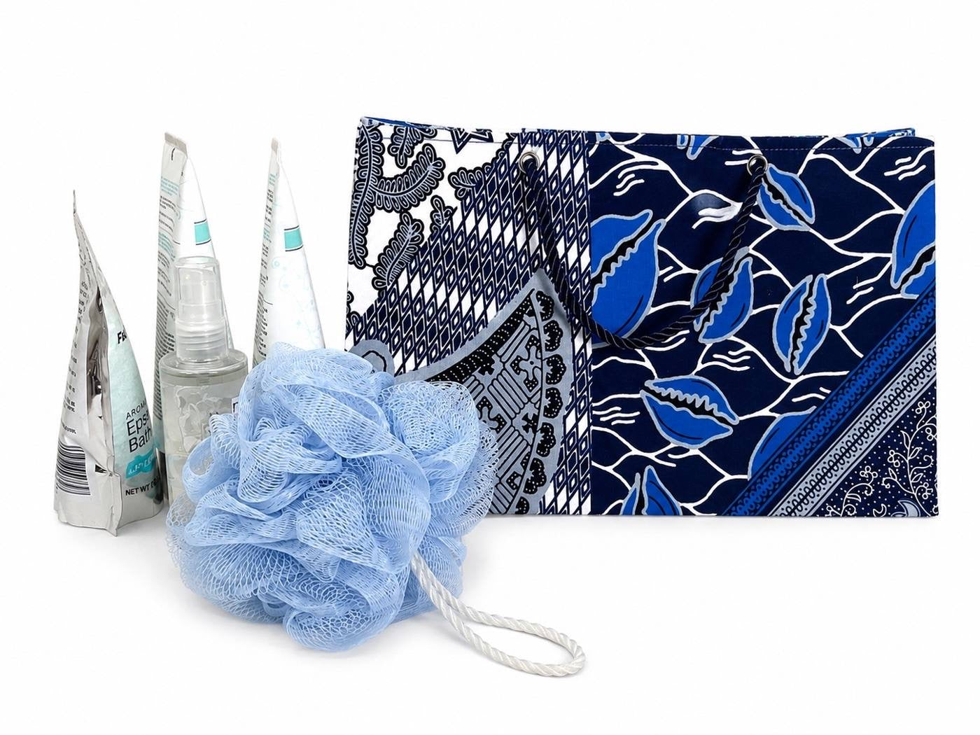 Blue. gray and white patterned medium horizontal gift bag with a blue loofah and bottles on a white background