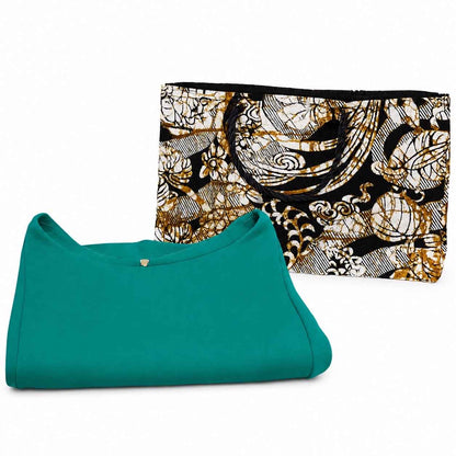 Cream, black, and gold handmade African fabric medium horizontal gift bag in lifestyle shot with a green dress