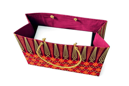 Inside view of a maroon, red and gold decorative gift bag with a white box inside and a handle on a white background