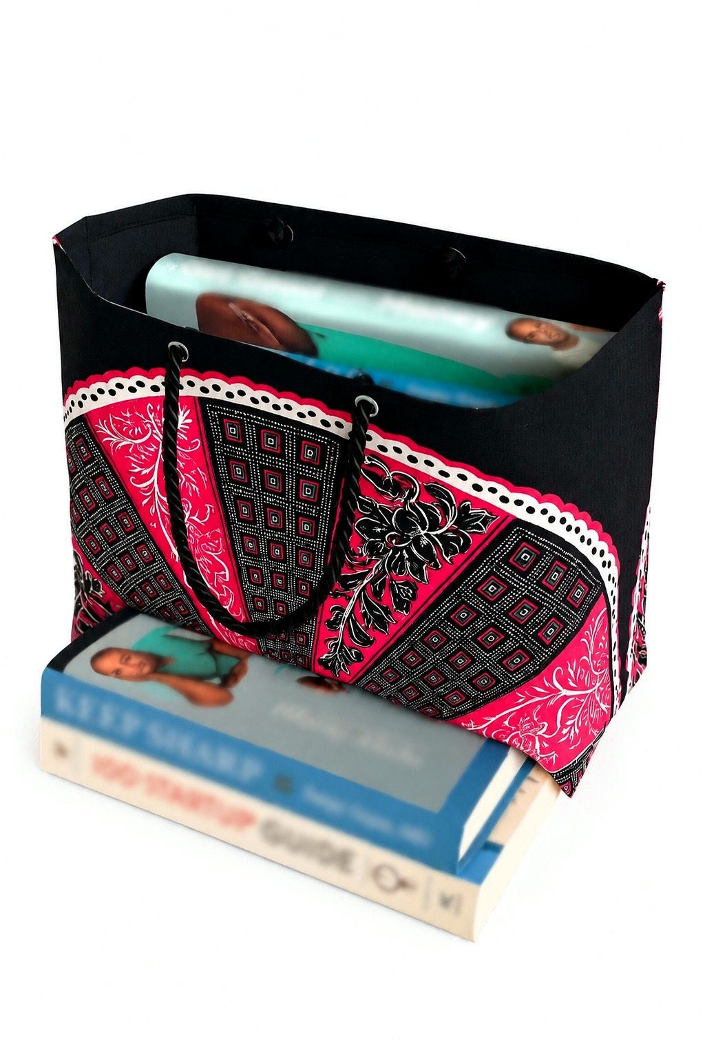 Black, white and fuchsia patterned bag with books inside on a white background