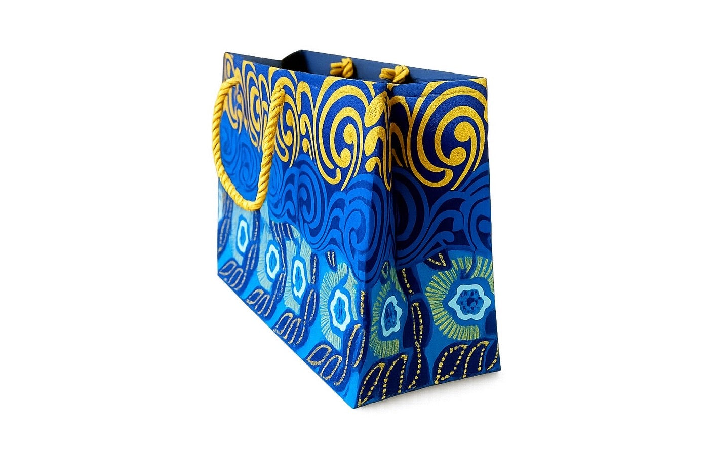Blue, dark blue, white, and gold  patterned bag with yellow handles on a white background