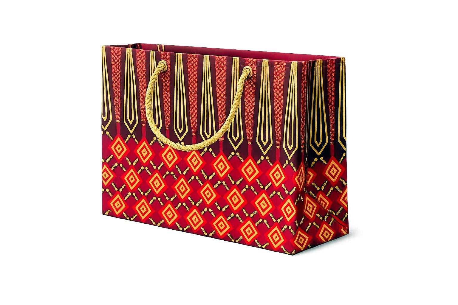 Decorative maroon, red and gold horizontal gift bag with geometric pattern on a white background