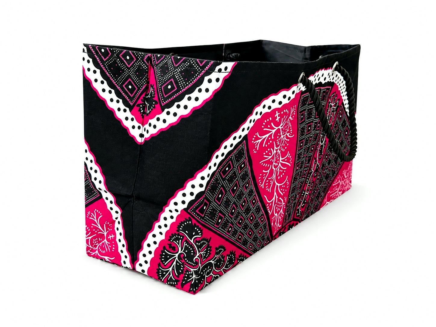 Side view of a black, pink, and white patterned gift bag on a white background