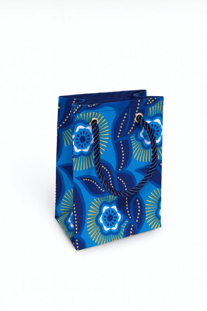 Blue decorative gift bag with dark blue, white, & gold pattern on a white background