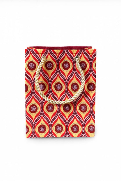 Decorative gift bag with red, purple, maroon, beige & silver pattern on a white background