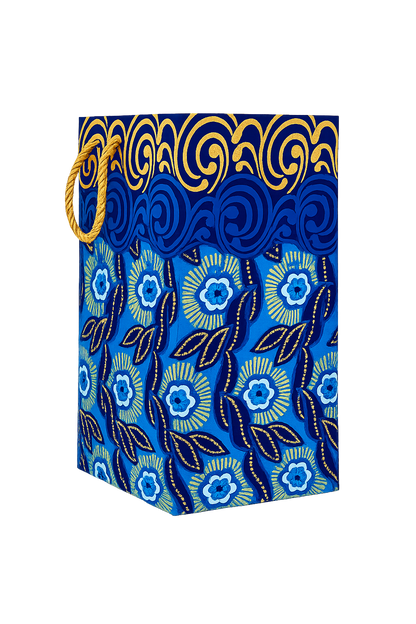 Side view of a blue decorative gift bag with white floral pattern and gold accents on a white background