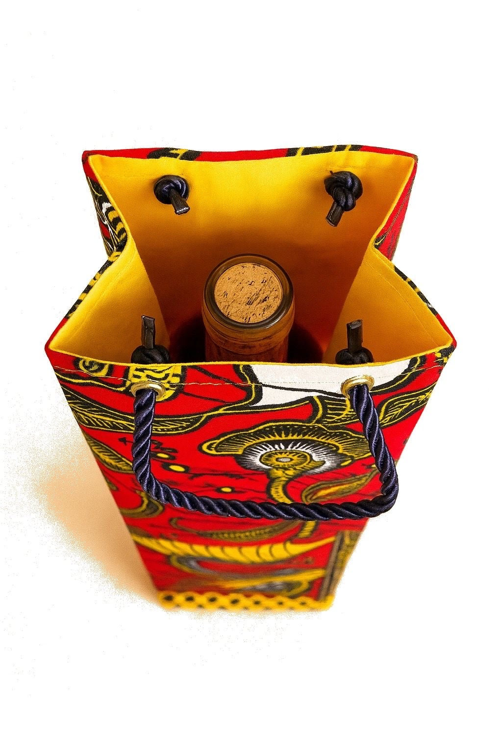 Decorative white, red, yellow, and dark blue wine bottle gift bag with intricate patterns on a white background