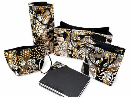 Set of cream, black, and gold bags and a notebook with black and gold bookmark on a white background