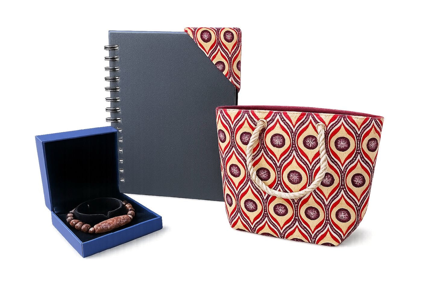 Set of items including a notebook with a corner bookmark, jewelry box with a bracelet, and cream, red, deep purple, and white patterned bag on a white background