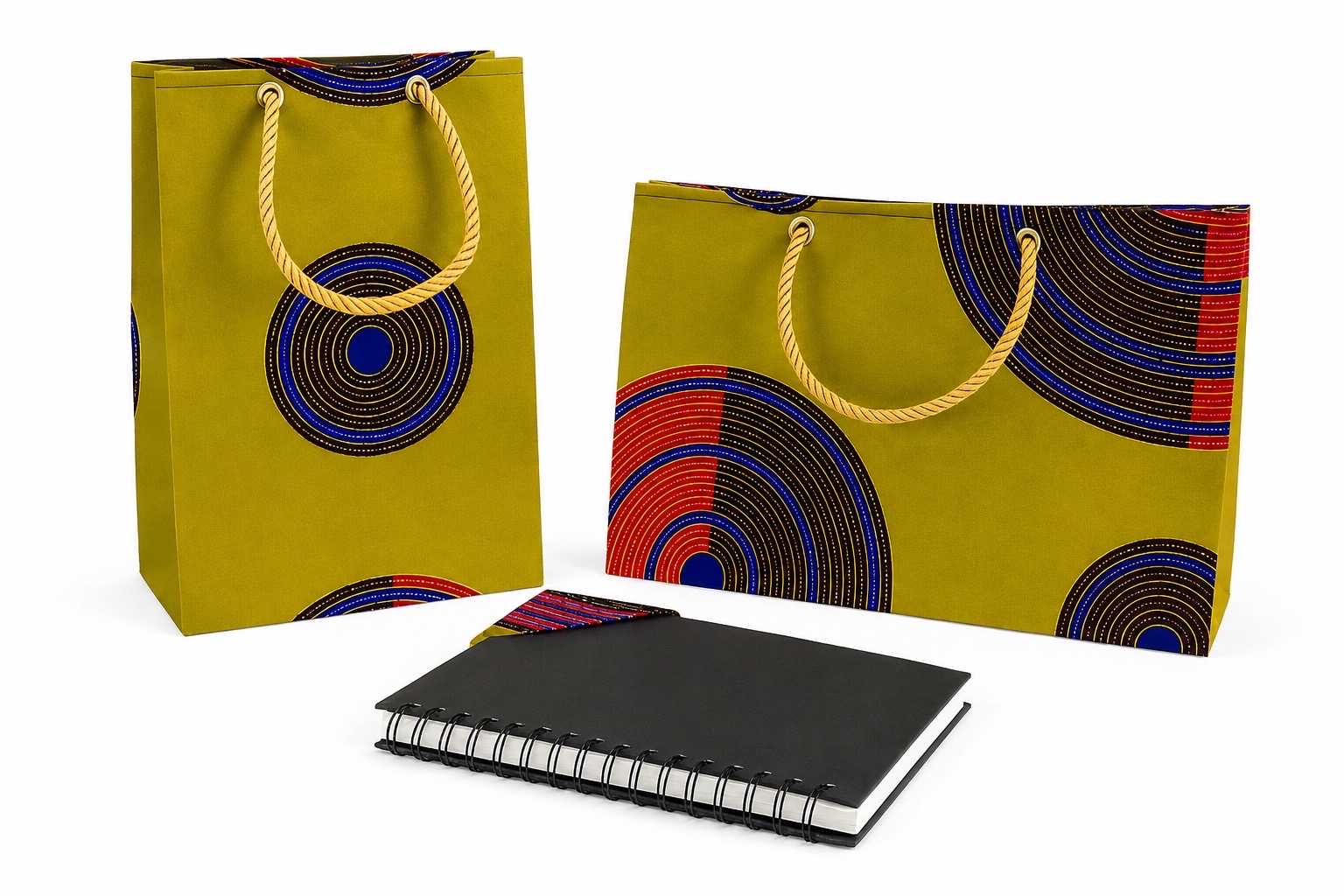 Two colorful green, dark brown, blue, red, and gold bags with circular patterns and a black notebook with a matching bookmark on a white background
