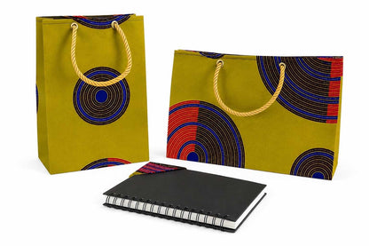 Two colorful green, dark brown, blue, red, and gold bags with circular patterns and a black notebook with a matching bookmark on a white background