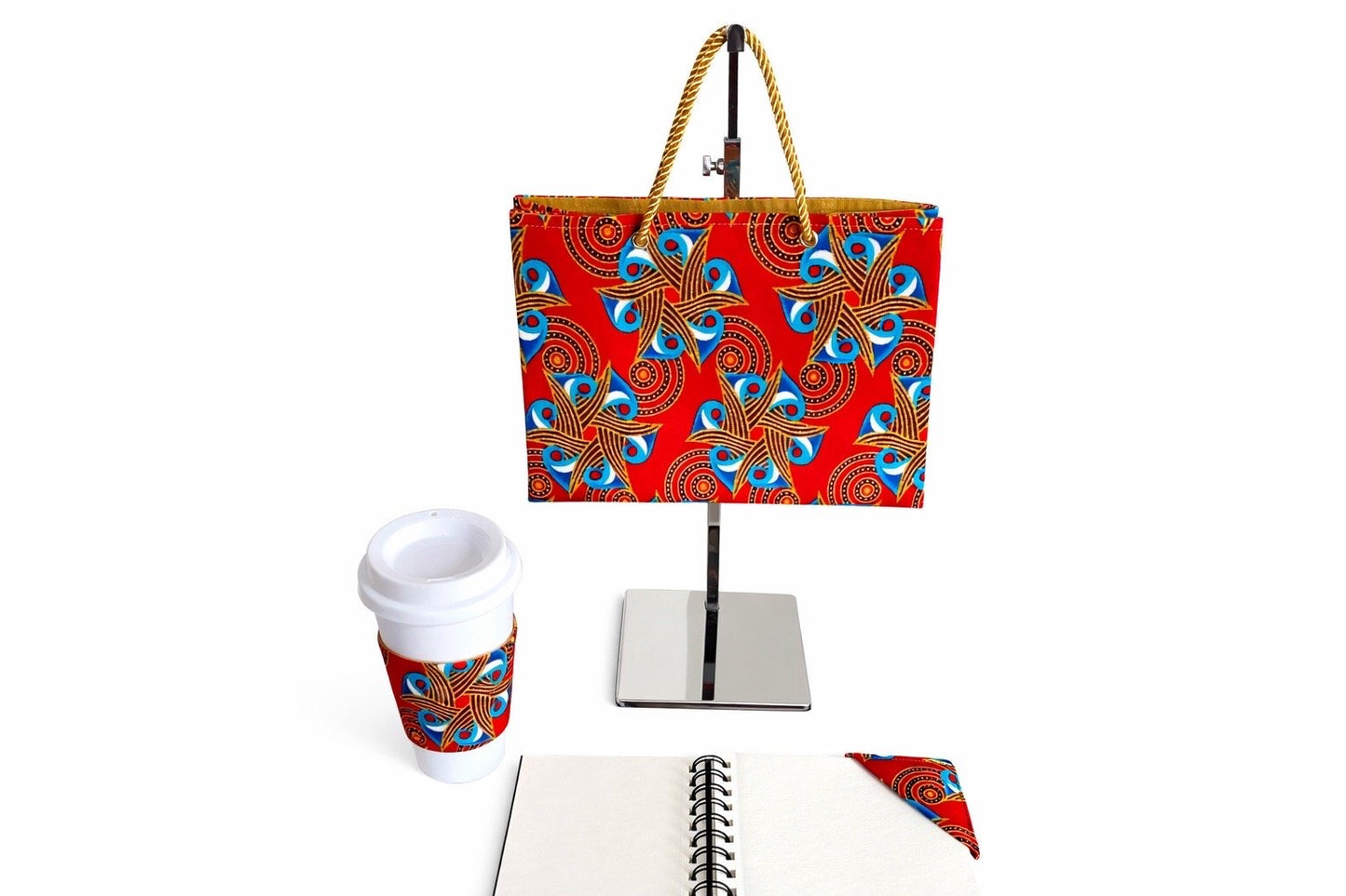Red, blue, white, & gold small horizontal bag, cup sleeve, & bookmark on a white background