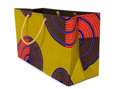 Side view of a decorative gift bag with green, dark brown, red, blue, and gold pattern on a white background