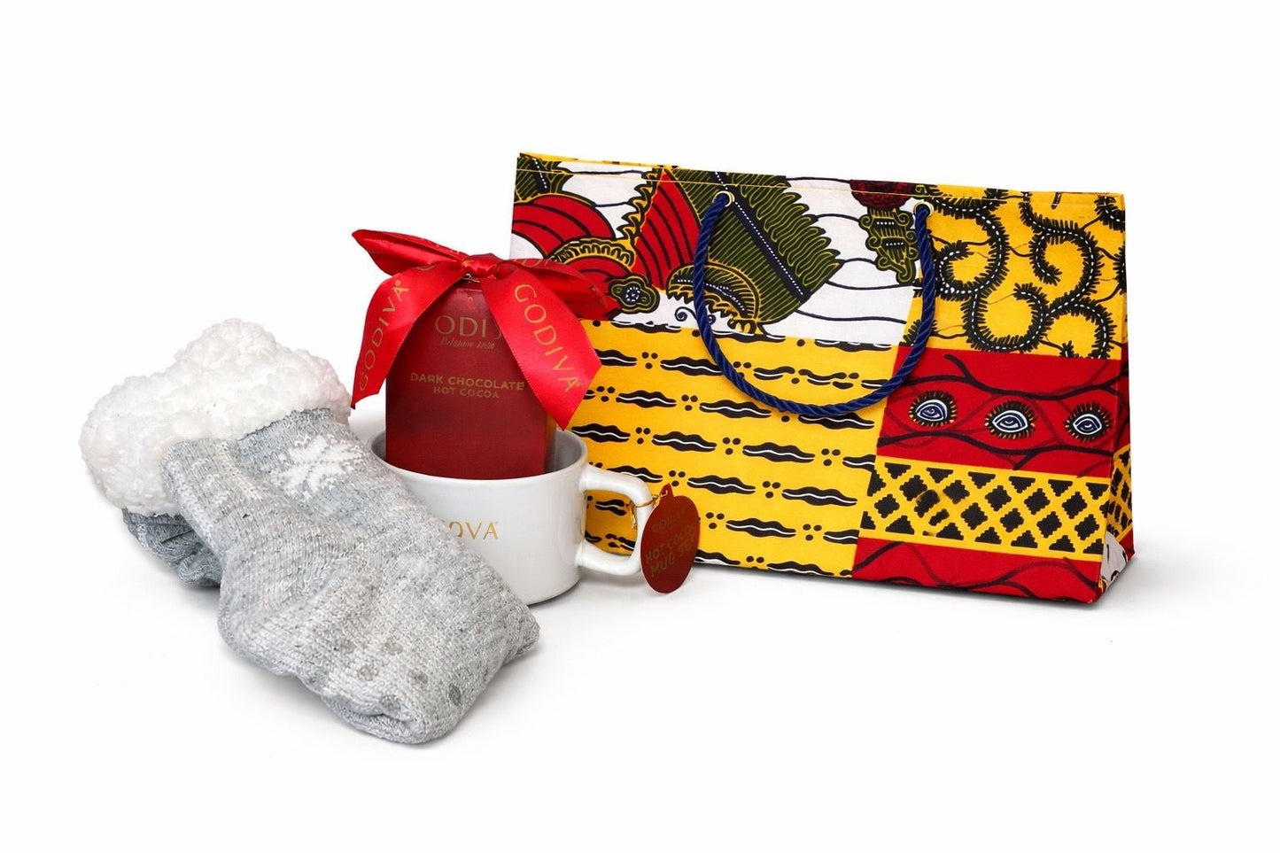 Set of socks, a mug with chocolates, and a colorful red, yellow, white, and dark blue patterned bag on a white background