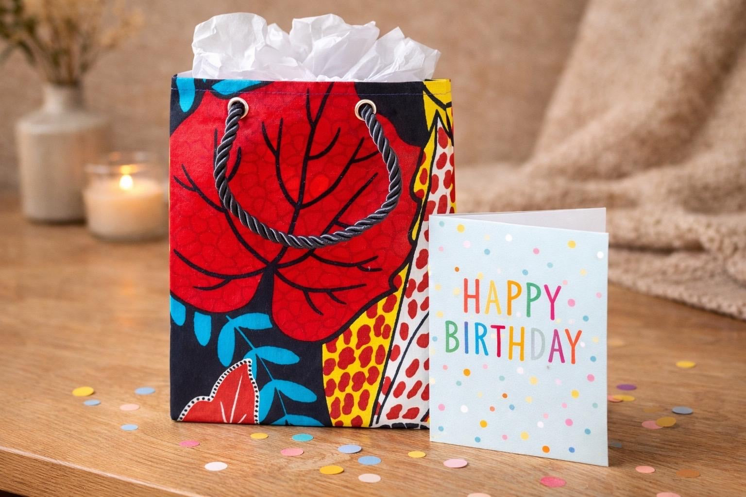 Red, black, aqua, yellow, & white extra small gift bag with product ideas inside the bag on a white background