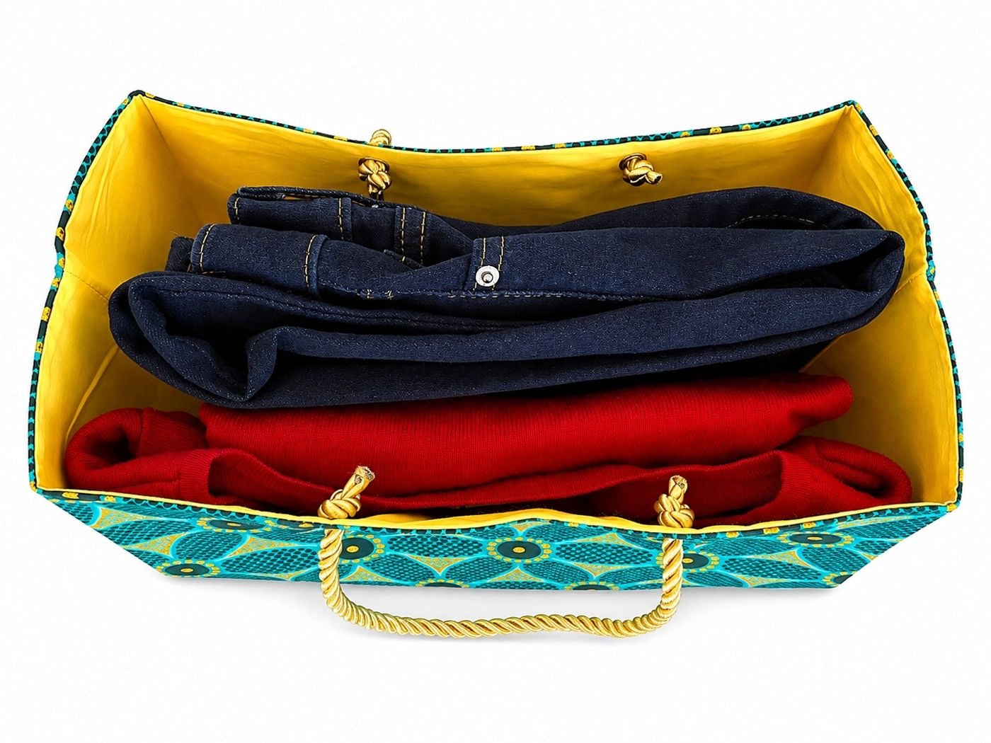 Colorful green, dark green, and gold gift bag with folded clothes inside on a white background
