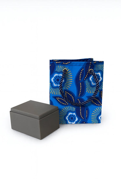 Dark blue, blue, white, & gold mini gift bag with product ideas on the side on a white background