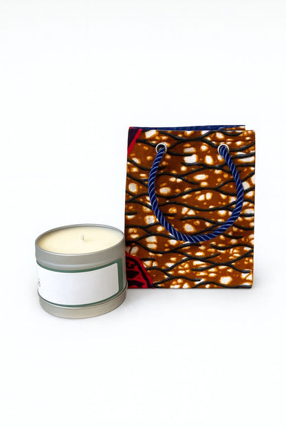 Candle in a tin with a decorative dark blue, dark brown, maroon, & cream bag on a white background