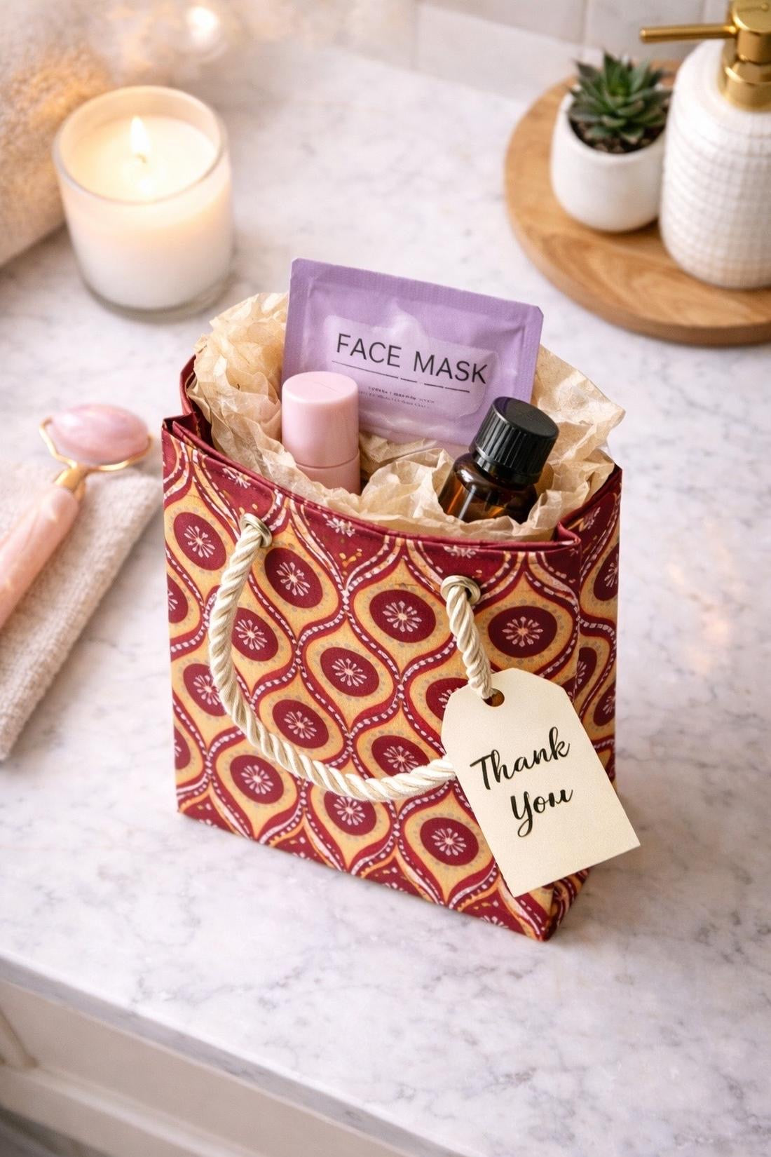 Maroon, red, purple, beige, & silver mini gift bag with product ideas to gift inside with a spa-like background