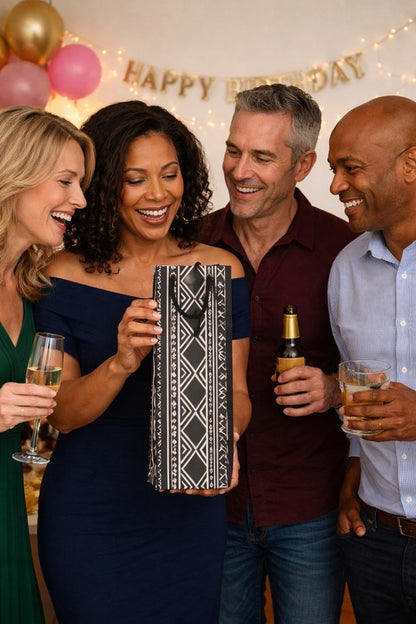 Group of four people celebrating a birthday with a decorated room and black and white wine gift bag.