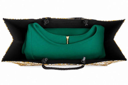 Inside view of a cream, black, and gold bag with black and gold accents and a green dress inside on a white background