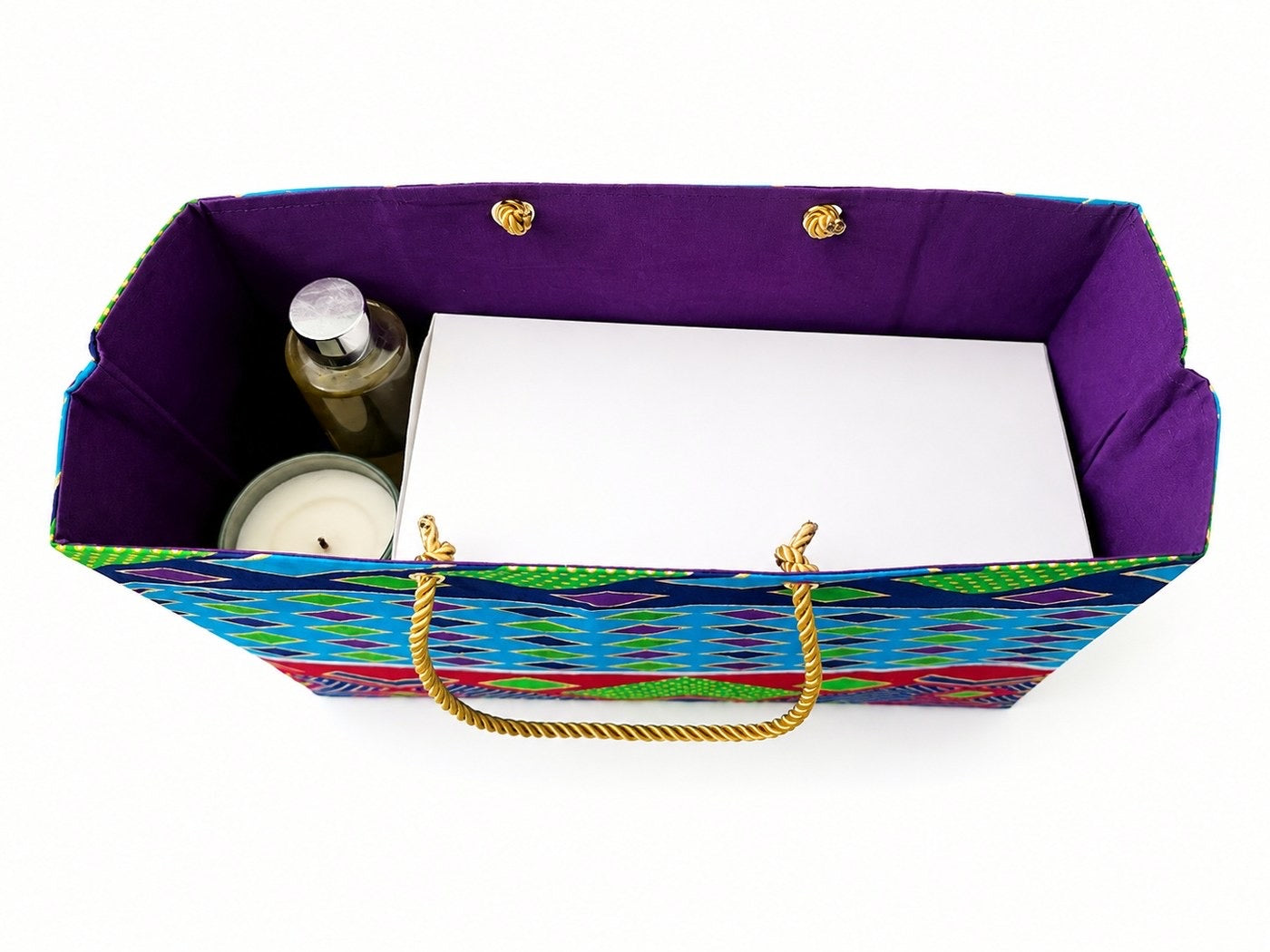 Colorful horizontal gift bag with a purple interior, gold handles, and a candle and bottle on a white background