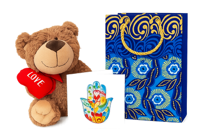Plush teddy bear with a heart, colorful hamsa hand, and decorative small blue bag on a white background