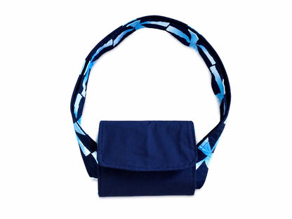 Navy blue and white bag with a blue and white patterned strap on a white background in folded position for carrying