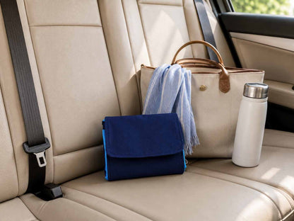 Blue and white foldable market bag in pouch position, beige handbag, and white tumbler on a car seat