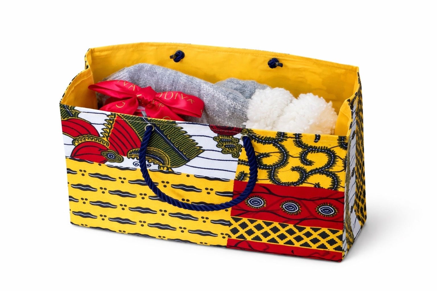 Inside view of set of socks, a mug with chocolates, and a colorful red, yellow, white, and dark blue patterned bag on a white background