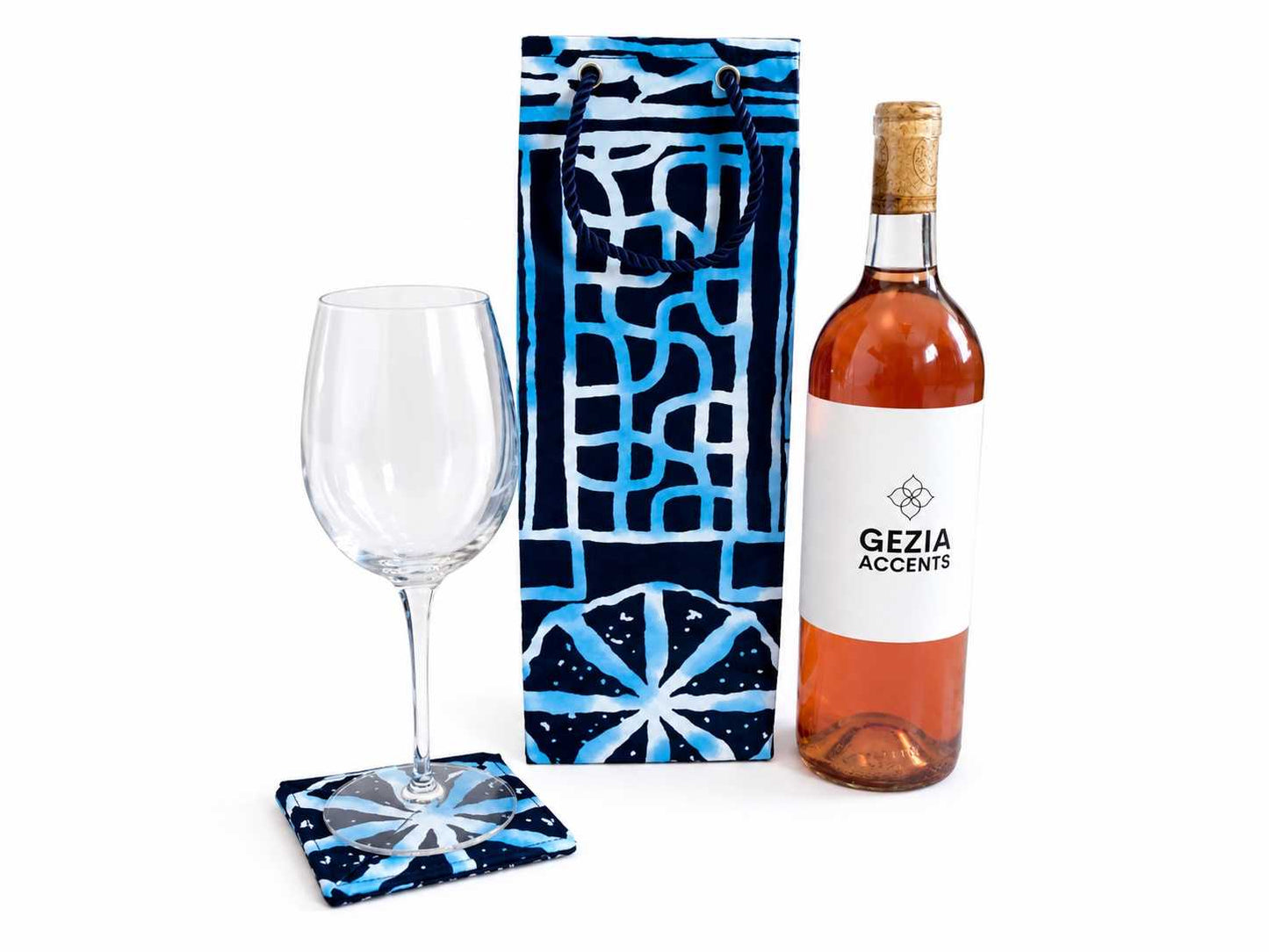 Wine bottle, glass, and coasters with a decorative gift bag on a white background