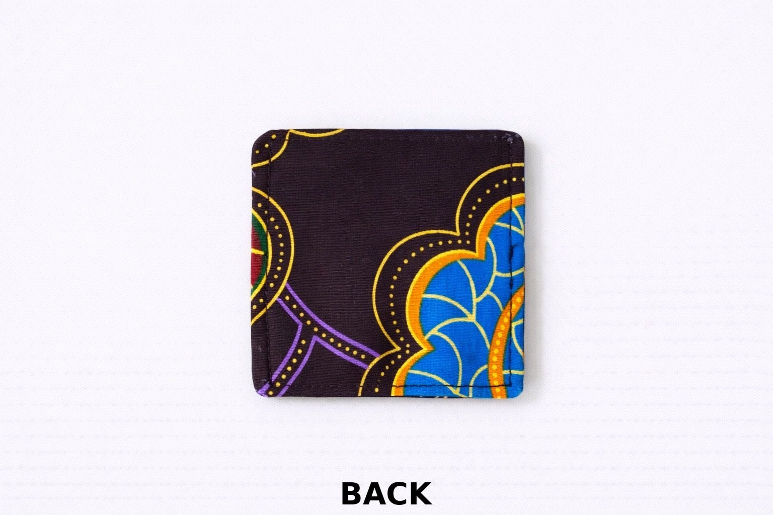 back view of dark brown corner bookmark with blue, red, & yellow patterns on a light gray background 