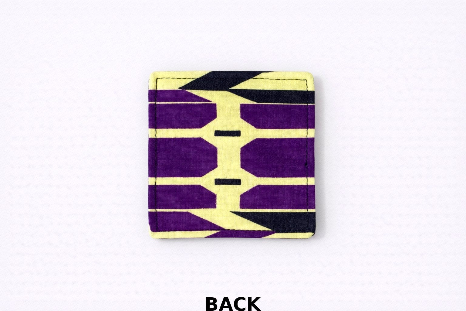 back view of yellow corner bookmark with purple & black patterns on a light gray background
