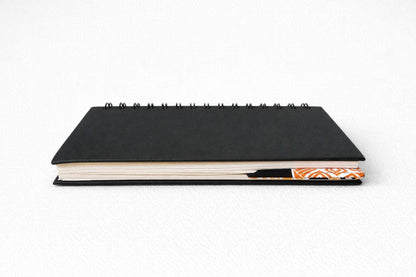 Black notebook with a decorative corner bookmark on a white background