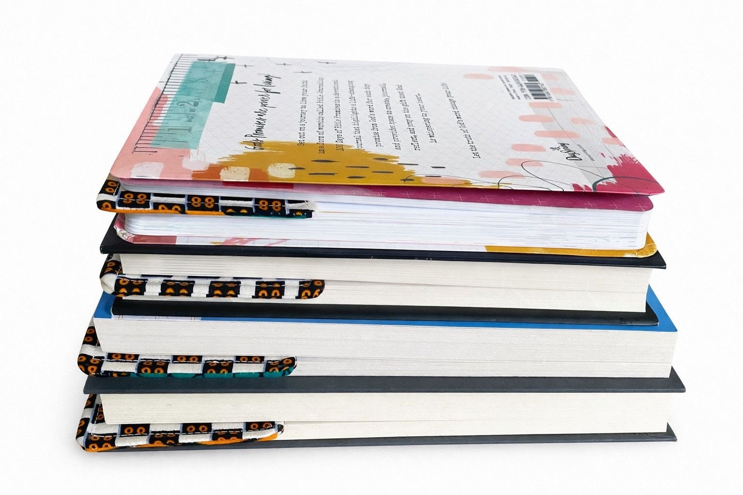 Books with a cream corner bookmarks in green, blue, & orange accents in-between the pages on a gray background