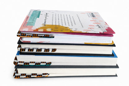 Books with a cream corner bookmarks in green, blue, & orange accents in-between the pages on a gray background