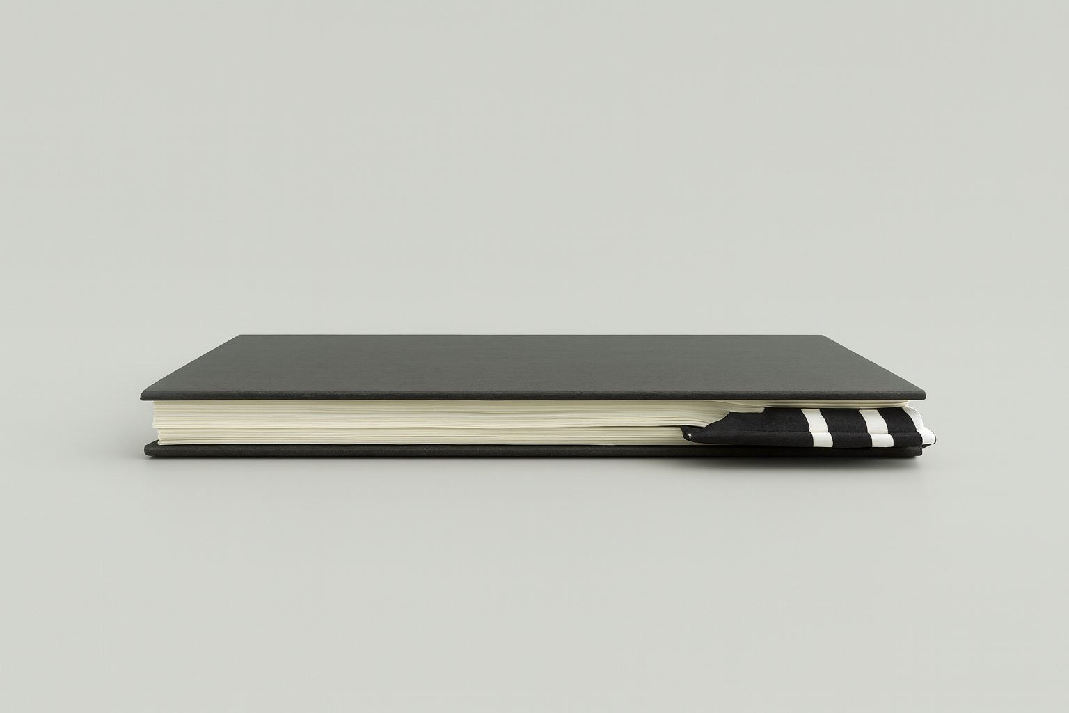 Black notebook with a black corner bookmark with white accents on a gray background