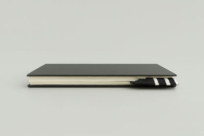 Black notebook with a black corner bookmark with white accents on a gray background