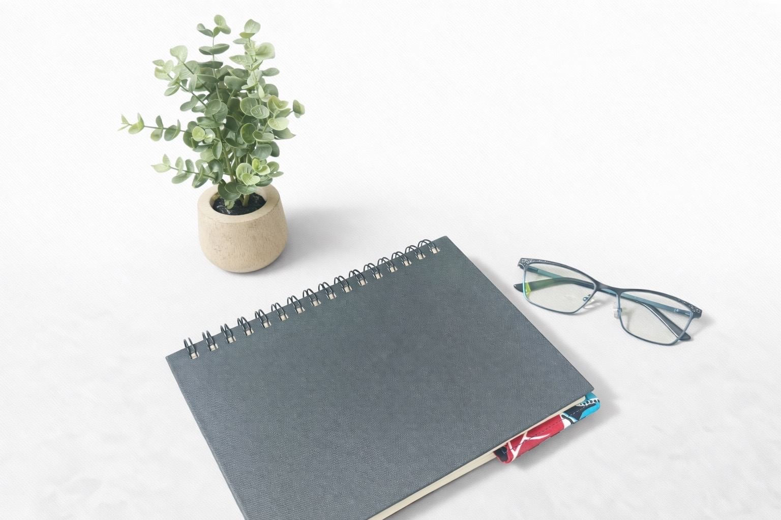 Black notebook with a corner bookmark in black, white, yellow, blue, & red accents on a gray background 