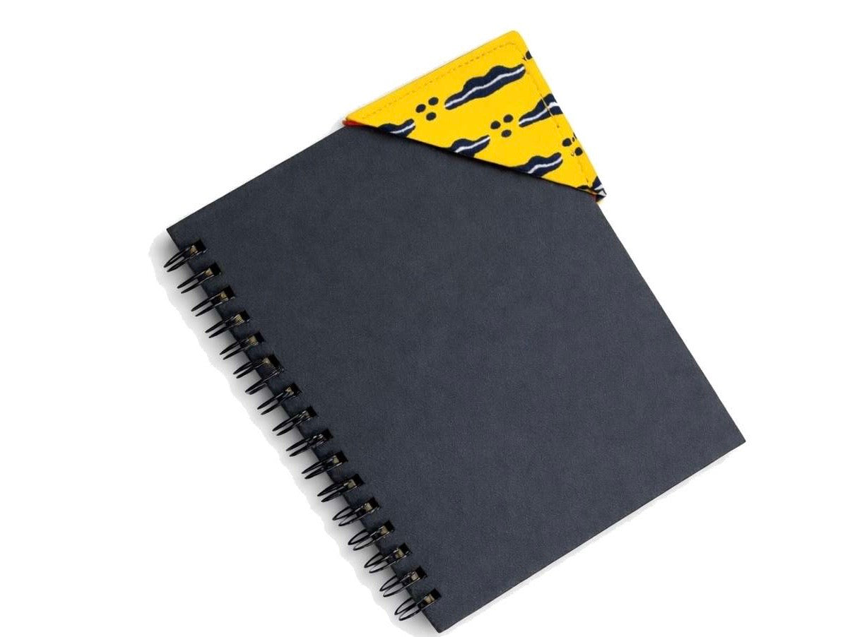 Black spiral-bound notebook with a yellow and blue corner bookmark on a light gray background