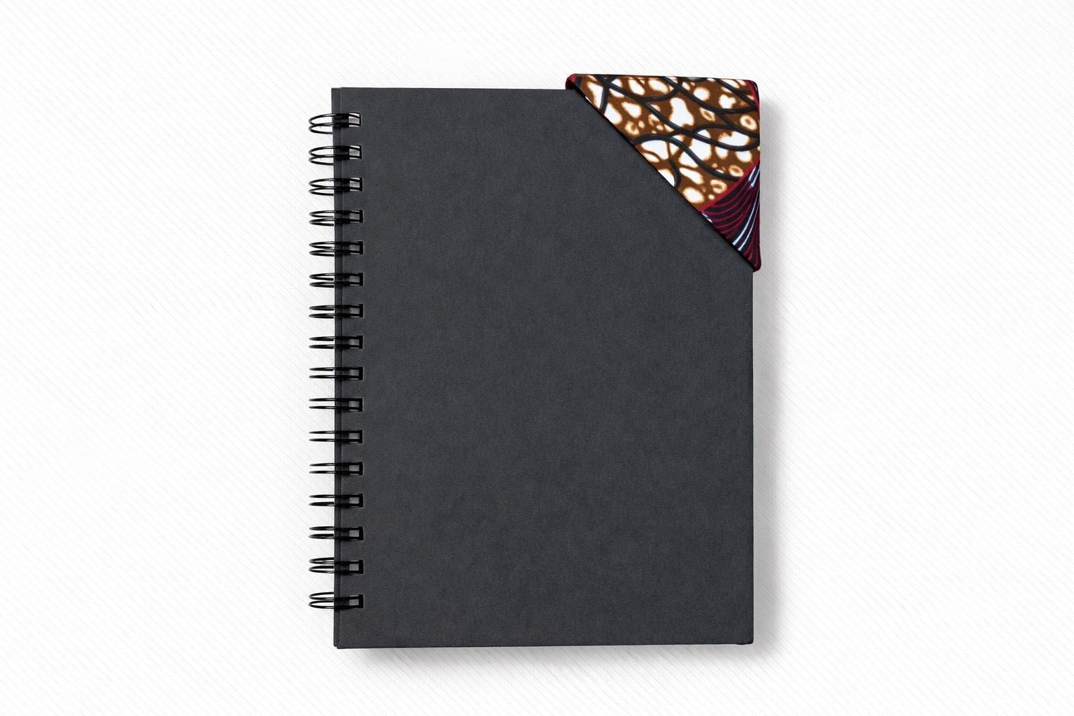 Black spiral-bound notebook with a brown, dark blue, maroon, & cream corner bookmark on a light gray background 