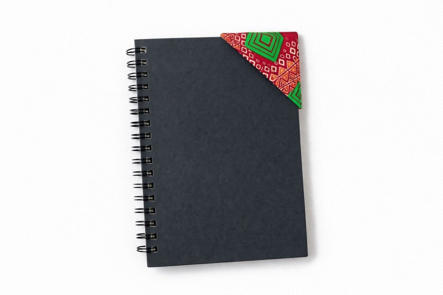Black spiral-bound notebook with a red, green, yellow & white corner bookmark on a light gray background
