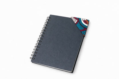 Black spiral-bound notebook with brown, maroon, turquoise, & white corner bookmark on a light gray background