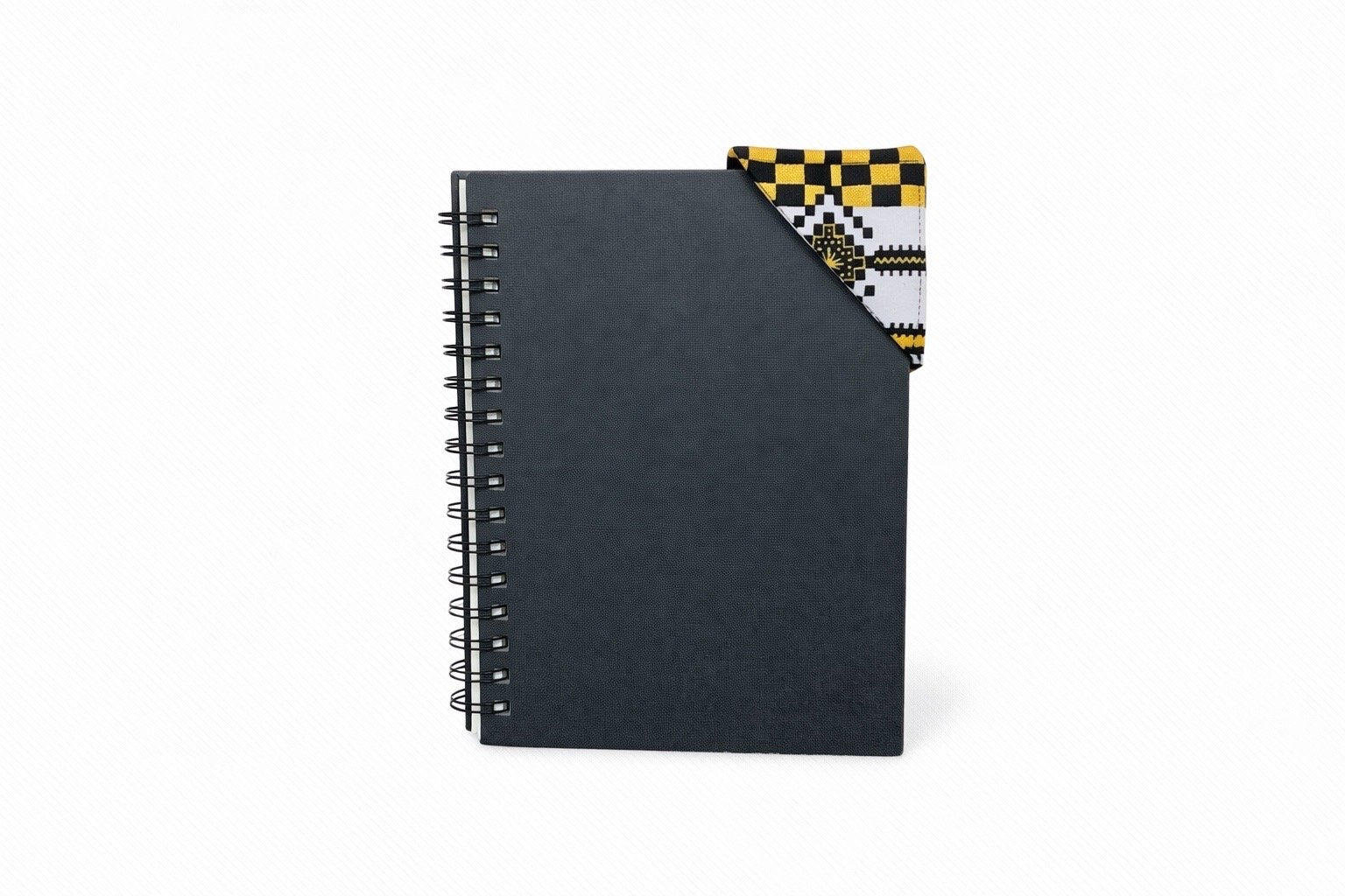 Black spiral-bound notebook with a white, black, & gold corner bookmark on a light gray background